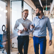 Two professional service consultants walking through modern office discussing client engagement
