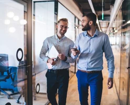 Two professional service consultants walking through modern office discussing client engagement