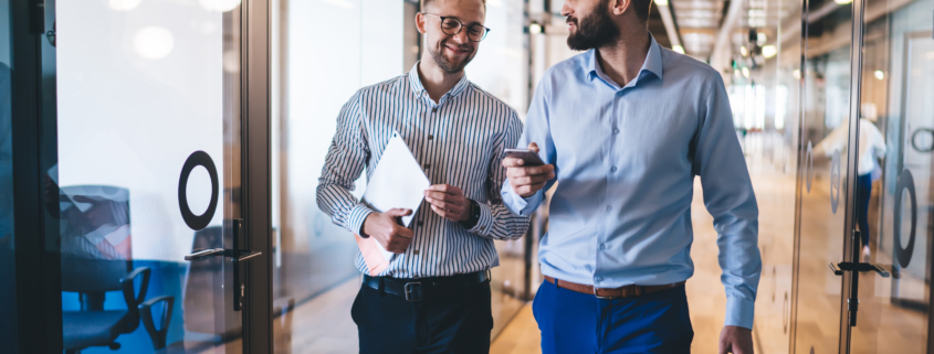 Two professional service consultants walking through modern office discussing client engagement